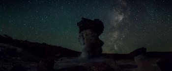 Movie still from “The Bad Batch” (2016), directed by Ana Lily Amirpour – A night sky filled with stars over a rock formation; Extreme Wide shot, Low angle