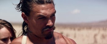 Movie still from “The Bad Batch” (2016), directed by Ana Lily Amirpour – A person with a beard and a mustache; Close Up shot, Over the shoulder angle