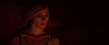 Movie still from “The Bad Batch” (2016), directed by Ana Lily Amirpour – A beautiful woman in a dimly lit room looking down; Close Up shot, Low angle