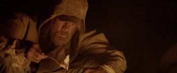 Movie still from “The Bad Batch” (2016), directed by Ana Lily Amirpour – A man with a beard wearing a hat and a jacket; Close Up shot, Low angle