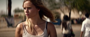 Movie still from “The Bad Batch” (2016), directed by Ana Lily Amirpour – A beautiful young woman with long , blonde hair walking down a street; Close Up shot, Over the shoulder angle