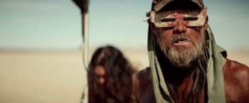 Movie still from “The Bad Batch” (2016), directed by Ana Lily Amirpour – A man with a beard and bandage on his face; Close Up shot, Low angle