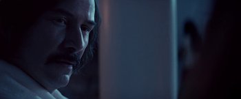 Movie still from “The Bad Batch” (2016), directed by Ana Lily Amirpour – A person with long hair and a beard; Close Up shot, Over the shoulder angle
