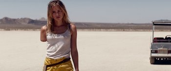 Movie still from “The Bad Batch” (2016), directed by Ana Lily Amirpour – A woman standing on a beach in front of a body of water; Medium shot, Low angle