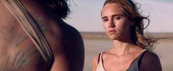 Movie still from “The Bad Batch” (2016), directed by Ana Lily Amirpour – A woman standing next to another woman on a beach; Close Up shot, Over the shoulder angle
