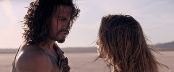 Movie still from “The Bad Batch” (2016), directed by Ana Lily Amirpour – A man and a woman standing next to each other in the desert; Close Up shot, Over the shoulder angle