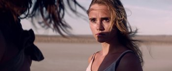 Movie still from “The Bad Batch” (2016), directed by Ana Lily Amirpour – A person wearing a tank top near a tree; Close Up shot, Over the shoulder angle