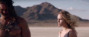 Movie still from “The Bad Batch” (2016), directed by Ana Lily Amirpour – A woman standing next to a man in front of a mountain range; Close Up shot, Over the shoulder angle