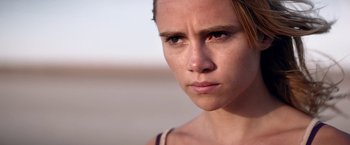 Movie still from “The Bad Batch” (2016), directed by Ana Lily Amirpour – A woman's face looking at the camera; Close Up shot, Low angle