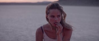 Movie still from “The Bad Batch” (2016), directed by Ana Lily Amirpour – A beautiful young lady standing next to a body of water; Close Up shot, Over the shoulder angle