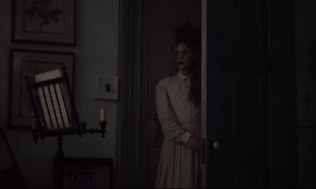 Movie still from “The Beguiled” (2017), directed by Sofia Coppola – A woman standing in front of a door in a dark room; Medium shot, Over the shoulder angle