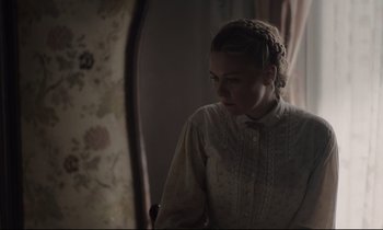 Movie still from “The Beguiled” (2017), directed by Sofia Coppola – A young woman looking in the mirror in front of a window; Medium shot, Over the shoulder angle
