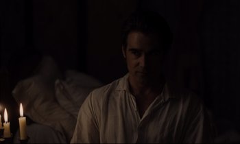 Movie still from “The Beguiled” (2017), directed by Sofia Coppola – A man sitting in a dark room looking at the camera; Medium shot, Over the shoulder angle