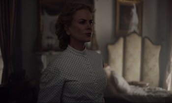 Movie still from “The Beguiled” (2017), directed by Sofia Coppola – A woman standing in a room with a couch in the background; Medium shot, Over the shoulder angle