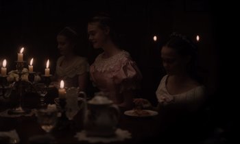Movie still from “The Beguiled” (2017), directed by Sofia Coppola – A group of people sitting at a table with candles in a dark room; Medium shot, Over the shoulder angle