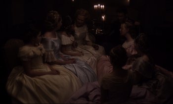 Movie still from “The Beguiled” (2017), directed by Sofia Coppola – A group of people sitting on a bed in a room; Wide shot, High angle