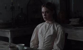 Movie still from “The Beguiled” (2017), directed by Sofia Coppola – A woman in a white dress sitting at a table with a cup of coffee; Medium shot, Over the shoulder angle
