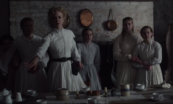 Movie still from “The Beguiled” (2017), directed by Sofia Coppola – A group of people standing around a dining room table; Medium shot, Low angle