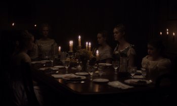 Movie still from “The Beguiled” (2017), directed by Sofia Coppola – A group of people sitting around a table with candles; Wide shot, Over the shoulder angle