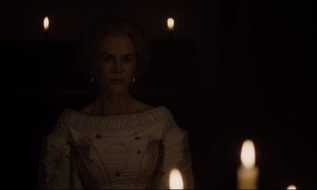 Movie still from “The Beguiled” (2017), directed by Sofia Coppola – A woman standing in front of candles in a dark room; Medium shot, Over the shoulder angle