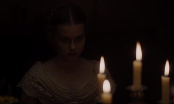 Movie still from “The Beguiled” (2017), directed by Sofia Coppola – A woman in a white dress is looking at two lit candles; Close Up shot, Over the shoulder angle