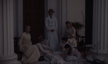 Movie still from “The Beguiled” (2017), directed by Sofia Coppola – A group of people sitting on the ground in front of a building; Wide shot, High angle