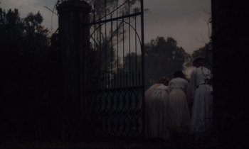Movie still from “The Beguiled” (2017), directed by Sofia Coppola – A group of people standing around a gate; Wide shot, High angle