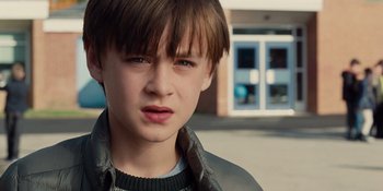 Movie still from “The Book of Henry” (2017), directed by Colin Trevorrow – A young boy with brown hair wearing a black jacket; Close Up shot, Over the shoulder angle
