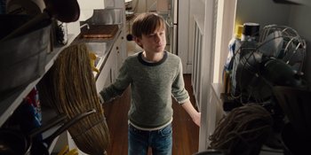 Movie still from “The Book of Henry” (2017), directed by Colin Trevorrow – A young boy standing in a kitchen next to a broom; Medium shot, Low angle