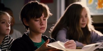 Movie still from “The Book of Henry” (2017), directed by Colin Trevorrow – A young boy is reading a book at a table; Close Up shot, Over the shoulder angle