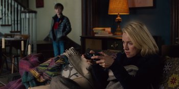Movie still from “The Book of Henry” (2017), directed by Colin Trevorrow – A woman sitting on a couch holding a remote control; Medium shot, High angle