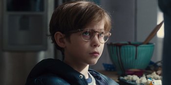 Movie still from “The Book of Henry” (2017), directed by Colin Trevorrow – A young boy wearing glasses and a blue jacket; Close Up shot, Over the shoulder angle