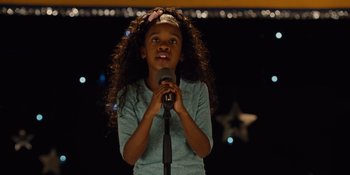 Movie still from “The Book of Henry” (2017), directed by Colin Trevorrow – A little girl is holding a microphone up to her mouth; Close Up shot, Over the shoulder angle