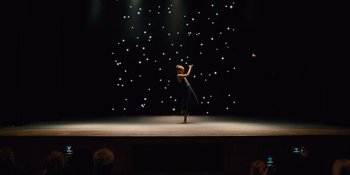 Movie still from “The Book of Henry” (2017), directed by Colin Trevorrow – A woman standing on one foot on a stage; Extreme Wide shot, Low angle