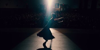 Movie still from “The Book of Henry” (2017), directed by Colin Trevorrow – A woman in a black dress on a stage with a crowd; Wide shot, Low angle
