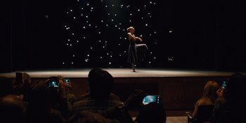 Movie still from “The Book of Henry” (2017), directed by Colin Trevorrow – A woman standing on a stage in front of a crowd; Wide shot, High angle