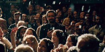 Movie still from “The Book of Henry” (2017), directed by Colin Trevorrow – A crowd of people sitting and standing in a room; Medium shot, Over the shoulder angle
