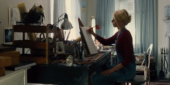 Movie still from “The Book of Henry” (2017), directed by Colin Trevorrow – A woman sitting at a desk in front of an open book; Medium shot, Low angle