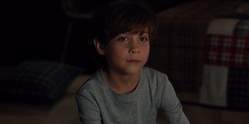 Movie still from “The Book of Henry” (2017), directed by Colin Trevorrow – A young boy sitting in a dark room; Close Up shot, High angle