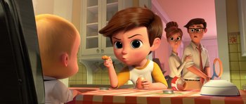 Movie still from “The Boss Baby” (2017), directed by Tom McGrath – A boy eating a piece of pizza at a table; Medium shot, Over the shoulder angle