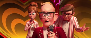 Movie still from “The Boss Baby” (2017), directed by Tom McGrath – An old man holding a microphone in front of two other people; Close Up shot, Over the shoulder angle