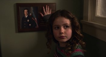 Movie still from “The Christmas Chronicles” (2018), directed by Clay Kaytis – A young girl is standing in front of a picture of an officer; Close Up shot, Over the shoulder angle