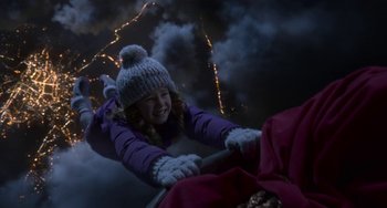 Movie still from “The Christmas Chronicles” (2018), directed by Clay Kaytis – A young girl in a purple jacket and a hat riding a bike; Medium shot, High angle