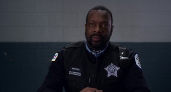 Movie still from “The Christmas Chronicles” (2018), directed by Clay Kaytis – A man in a police uniform sitting in front of a brick wall; Close Up shot, High angle