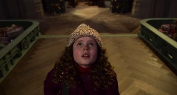 Movie still from “The Christmas Chronicles” (2018), directed by Clay Kaytis – A little girl wearing a knitted hat looking up at the camera; Close Up shot, High angle