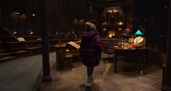 Movie still from “The Christmas Chronicles” (2018), directed by Clay Kaytis – A woman in a purple jacket walking in a room with a fire place; Wide shot, High angle
