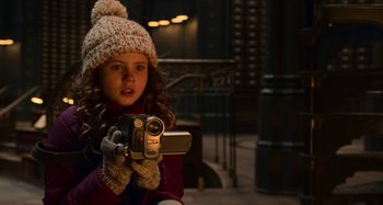 Movie still from “The Christmas Chronicles” (2018), directed by Clay Kaytis – A little girl holding a video camera in her hands; Close Up shot, High angle
