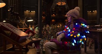 Movie still from “The Christmas Chronicles” (2018), directed by Clay Kaytis – A little girl sitting in a chair wearing a hat with lights on it; Medium shot, Over the shoulder angle