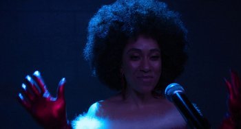 Movie still from “The Christmas Chronicles” (2018), directed by Clay Kaytis – A woman in a white dress is holding a microphone; Close Up shot, Over the shoulder angle