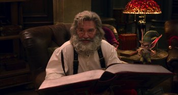 Movie still from “The Christmas Chronicles” (2018), directed by Clay Kaytis – An old man with a beard and glasses is reading a book; Medium shot, Over the shoulder angle